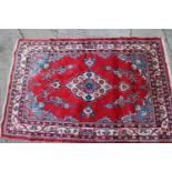 A "Persian" rug with central medallion on a scarlet ground, 56" x 85" approx