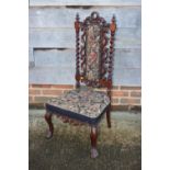 A 19th century carved rosewood framed low seat nursing chair with tapestry panel back and seat, on