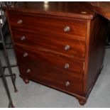 A mahogany bedside chest, fitted two deep drawers with brass knob handles, on turned supports, 25"