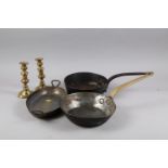 Two copper pans, a two-handled pan and a pair of turned brass candlesticks, 7 1/2" high
