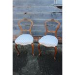 A pair of Victorian carved walnut loop back side chairs, on cabriole supports