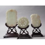 Three carved jade panels, on hardwood stands, largest 6" high overall