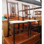 A set of four early 20th century walnut and inlaid vertical rail back side chairs with padded seats,