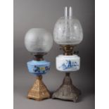 A brass oil lamp with etched shade and blue and white reservoir, decorated Dutch landscape and