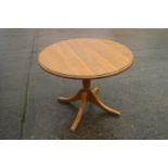 An oak circular top dining table with extra leaf, on turned column and quadruple splay supports, 36"