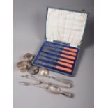 Three pairs of silver tongs, two napkin rings, a silver sifter spoon, a silver circular box (for