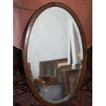 An oak oval framed wall mirror with bevelled plate, 26 1/2" x 16"