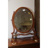A mahogany and inlaid oval swingframe toilet mirror, on skeleton stand