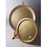 A Middle Eastern brass tray with engraved decoration, 22 1/2" dia, and another similar, 17" dia