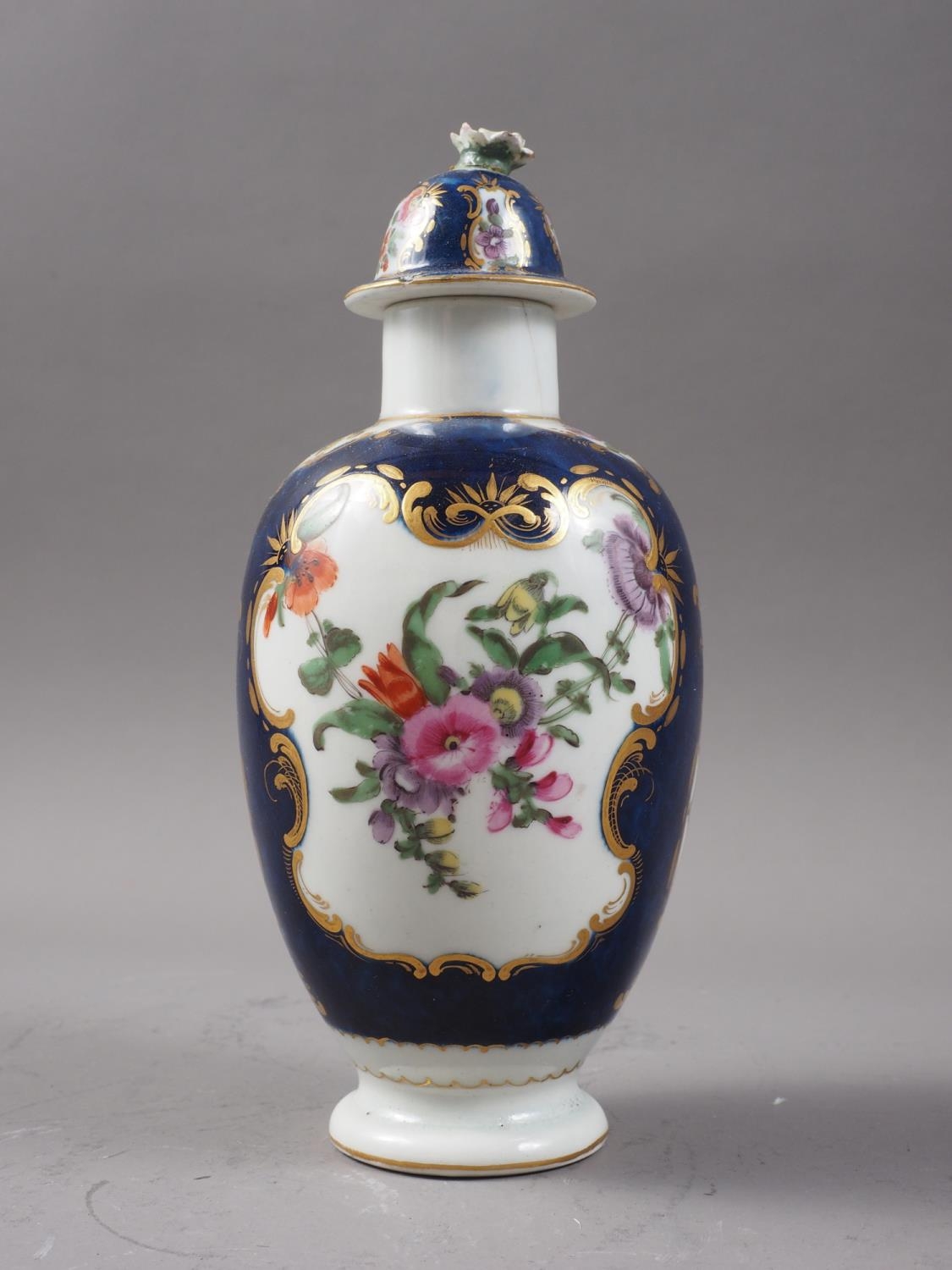 An 18th century Worcester oviform tea caddy with reserved floral panels on a blue scale ground