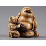 A Japanese carved ivory netsuke Hotei with acolyte painting on his stomach, signed, 1 1/4" high