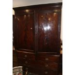 An early 19th century figured mahogany linen press, the upper section fitted trays enclosed two