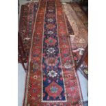 A Tabriz runner with seven octagonal guls and six white rosettes on a blue ground with floral