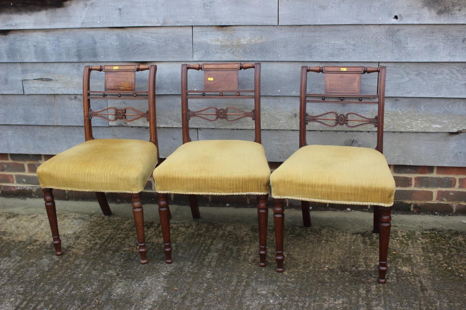 A set of three 19th century carved mahogany bar back dining chairs with stuffed over seats, on