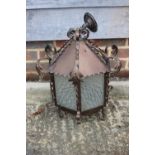 A wrought iron hexagonal ceiling lantern with acanthus leaf finials and engraved floral pattern