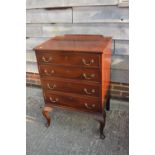 An early 19th century mahogany ledge back chest of four long graduated drawers with brass bail