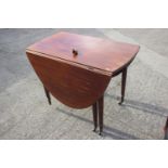 A mahogany oval drop leaf dining table, on turned and castored supports, 38" wide x 23" deep x 29