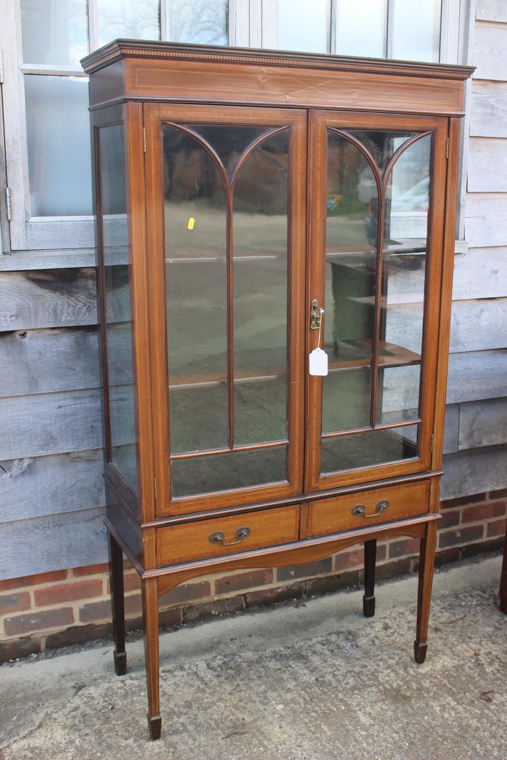 An Edwardian walnut banded and line inlaid display cabinet with astragal glazed doors enclosed two