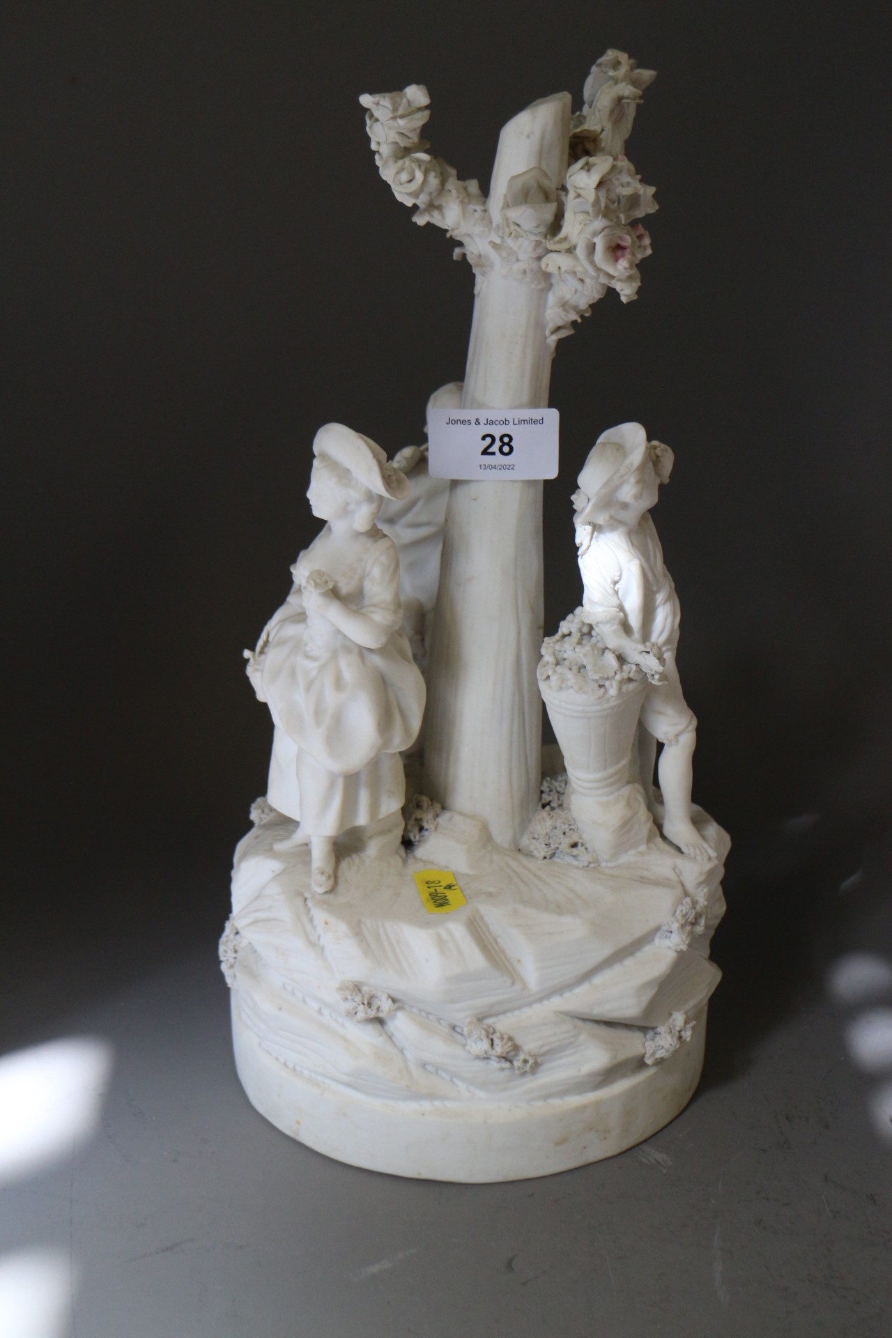 A late 18th century French bisque porcelain table centre, figures round a tree, on circular base,