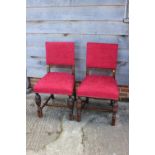 A pair of oak framed dining chairs, upholstered in a red fabric, on turned and fluted supports