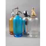 A blue glass soda siphon, an amber glass soda siphon and two other soda siphons