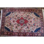A Kashan rug with red central medallion on a floral scroll and cream ground with triple floral