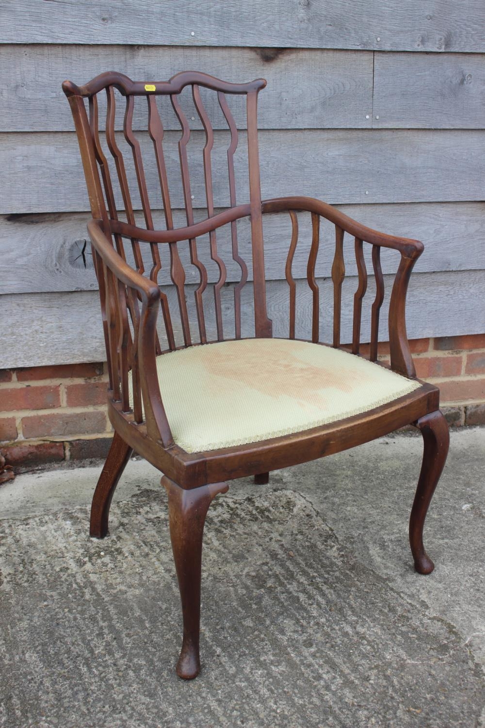 A late 19th century mahogany shaped vertical rail back open armchair with padded seat, on cabriole