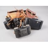 Two Vest pocket cameras, in leather cases and a pair of binoculars