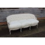 A dove grey painted showframe settee of Louis XVI design, button upholstered in a cotton ticking