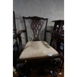 A pair of carved mahogany elbow chairs of Chippendale design with pierced splat backs and drop-in