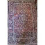 An antique Persian rug with blue central medallion on a rust ground with all-over scroll design in