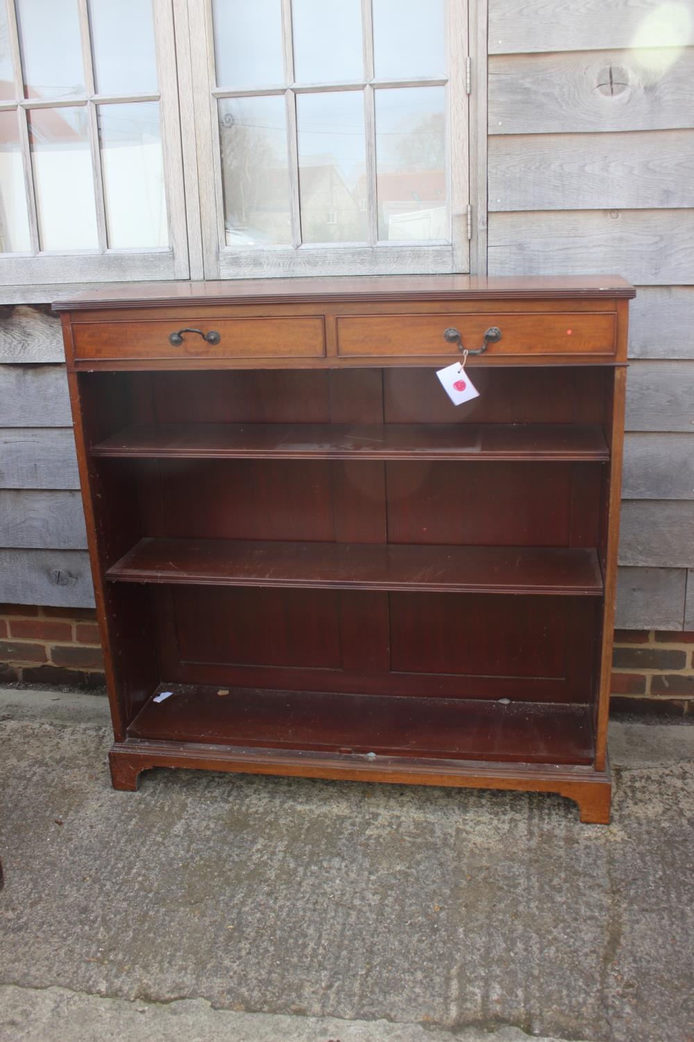A Maples late 19th century walnut bookcase, fitted two drawers over open shelves, on bracket feet,