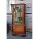 A mahogany two-section corner display cabinet, the upper section enclosed astragal glazed door