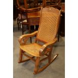 A Kashmir walnut scroll arm rocking chair with cane seat and back panels