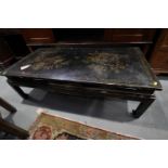 A Chinese black and gold lacquered low occasional table, on scroll end supports, 49" wide x 24" deep