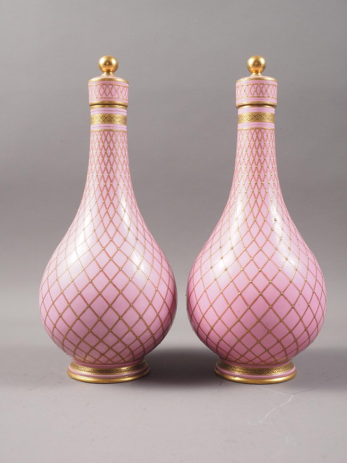 A pair of Sevres style porcelain bottle vases and covers with all-over lattice decoration on a