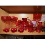 A collection of cranberry glass, including six wines, a pair of flared vases, a water jug, a