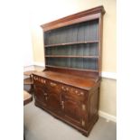 A George III oak dresser, fitted shelves over three drawers and two cupboards enclosed arched