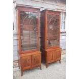 A pair of George III figured mahogany display cabinets enclosed Gothic lattice glazed panel doors