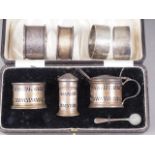 Four silver napkin rings, 3.4oz troy approx, and a cased silver three-piece cruet set