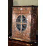 An Arts & Crafts embossed copper covered corner hanging cupboard enclosed oval leaded glazed panel