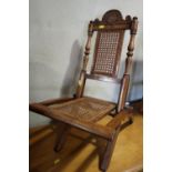 A child's Victorian polished as walnut folding chair with cane seat and back panels