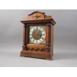 An oak cased mantel clock with brass and white enamelled dial and Roman numerals, 13 1/2" high