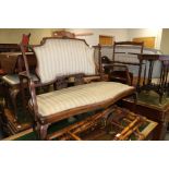 An Edwardian walnut two-seat settee with padded seat and back, upholstered in a Regency striped