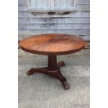 A 19th century mahogany circular dining table, on faceted column triform base with lion paw feet,