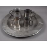 An 18th century pewter charger, 18" dia, and four later pewter tankards, two with glass bottoms