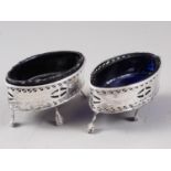 A pair of Georgian silver oval salts with pierced and engraved decoration and blue glass liners