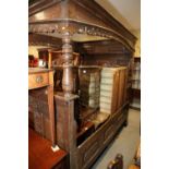 A 17th century carved oak fourposter bed with panelled back, fitting sliding cupboard and