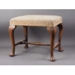 A carved walnut stool of Queen Anne design with needlepoint seat, on cabriole stretchered