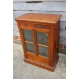 An Edwardian fruitwood, pine and oak side cupboard, fitted two drawers over glazed panel door and